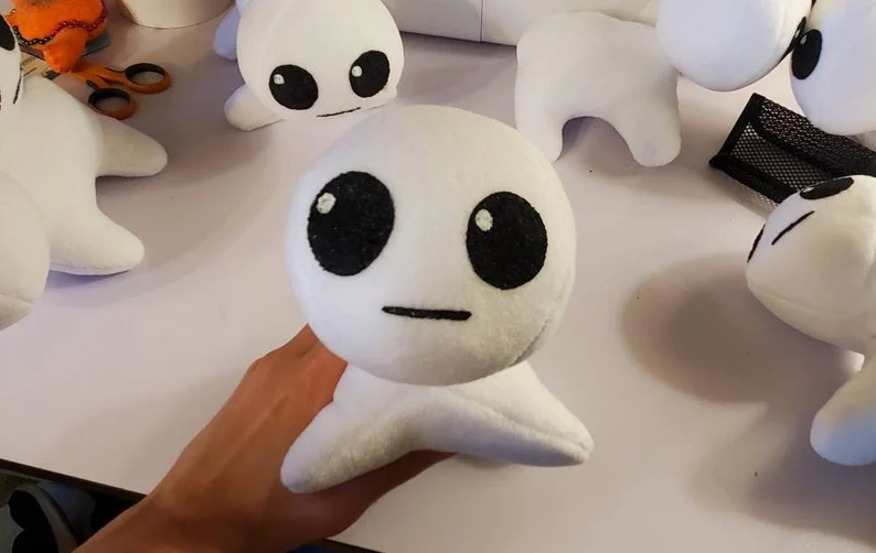 A photograph of a plush made by DayLikesCookies. The design is of the meme TBH creature, or the autism creature. It was designed by Acmeiku.