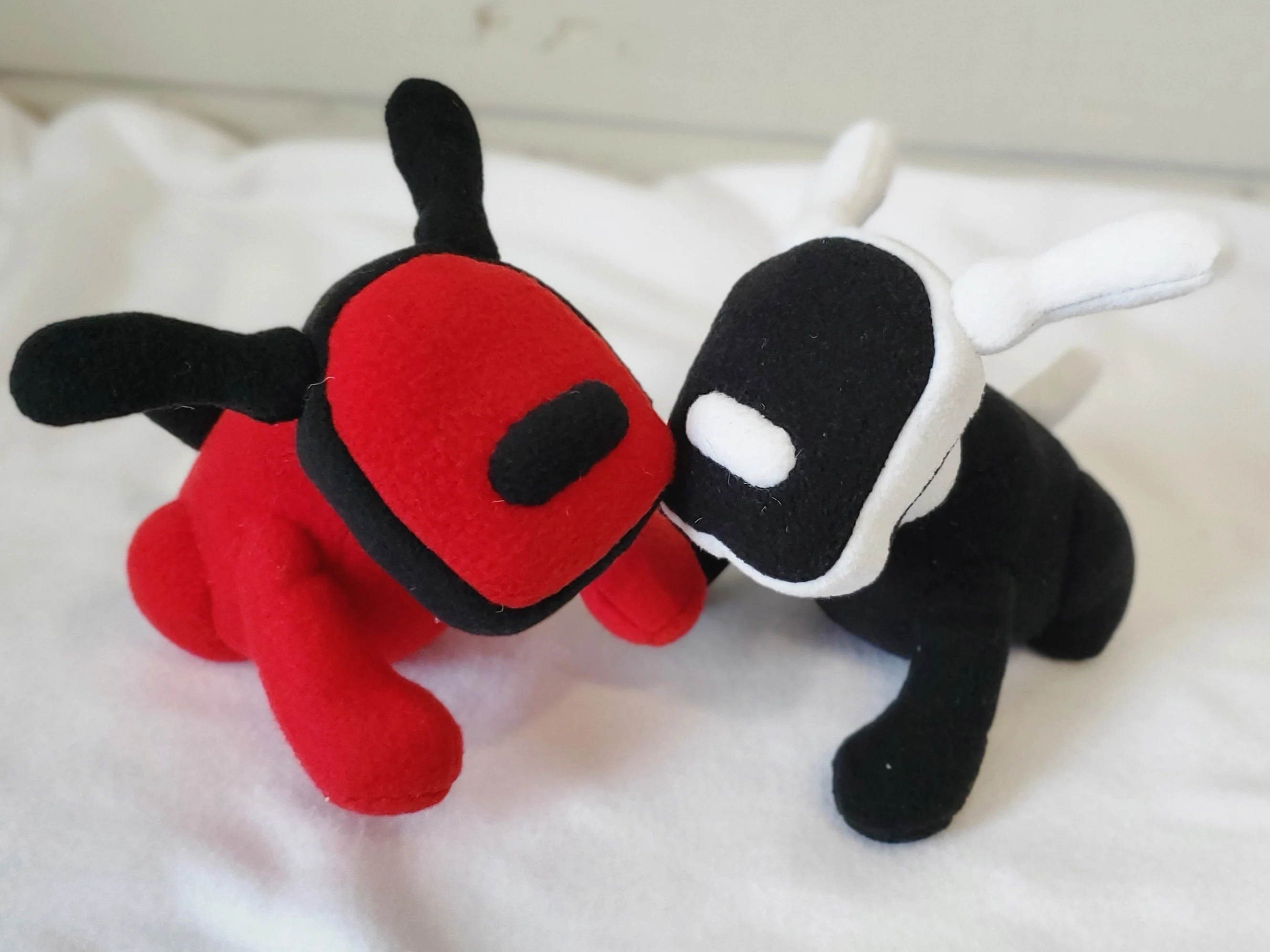 A photograph of two plushies made by DayLikesCookies. The design is of a retro robot dog.